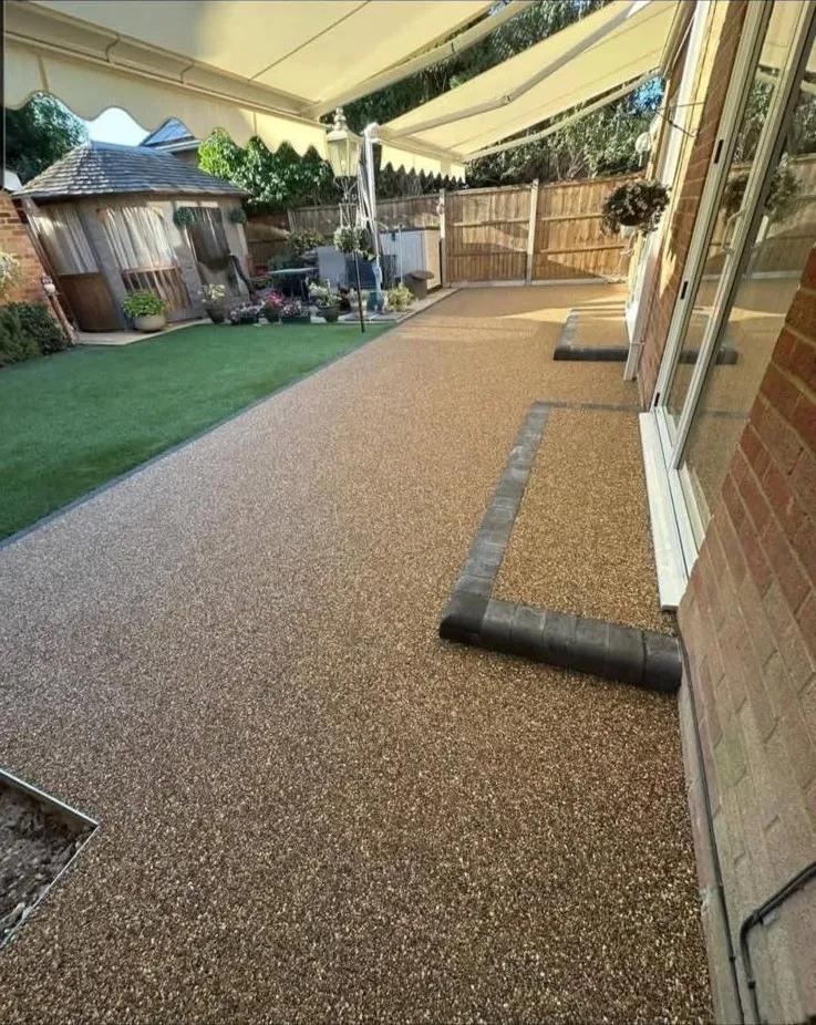 Smooth resin patio finish beside a lawn by Stoneage Property Care